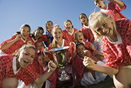 A youth sports team cheers as they hold a trophy