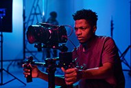 a filmmaker uses a camera with a stabilizer in a dim studio