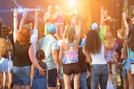 concert goers raise their hands and cheer for a show