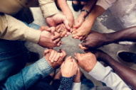 a group of diverse people hold hands in a circle