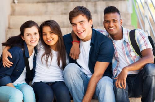 Group of diverse teenage students sitting together on steps