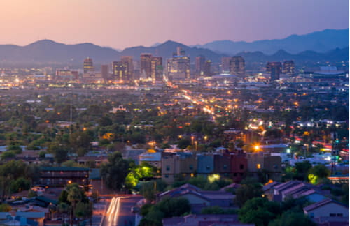 Skyline of Downtown Phoenix in the early dusk with mountains in background