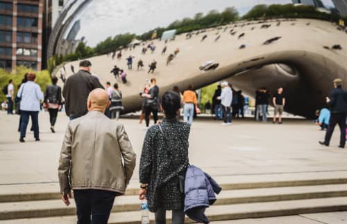 a couple stands admires Chicago's Cloud Gate sculpture from afar