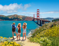 three women stand on a cliff overlooking the golden gate bridge and the Bay