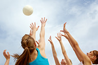 Volleyball players reach for a ball