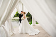 a couple in a white tent kiss on their wedding day