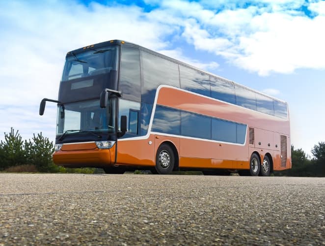An orange TDX double-decker charter bus drives on an open road