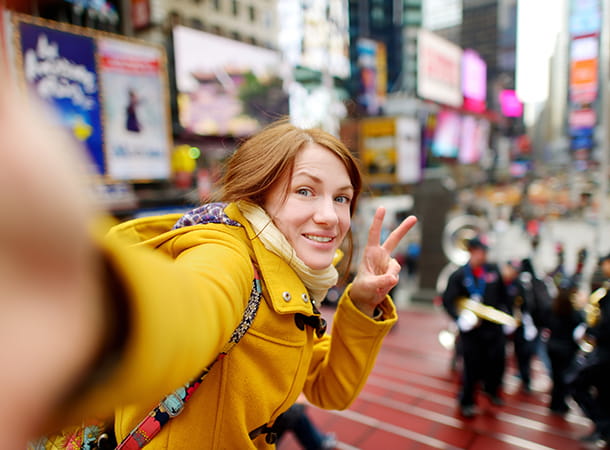 A tourist smiles for a selfie in Time Square