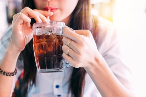 a woman sips coke from a glass