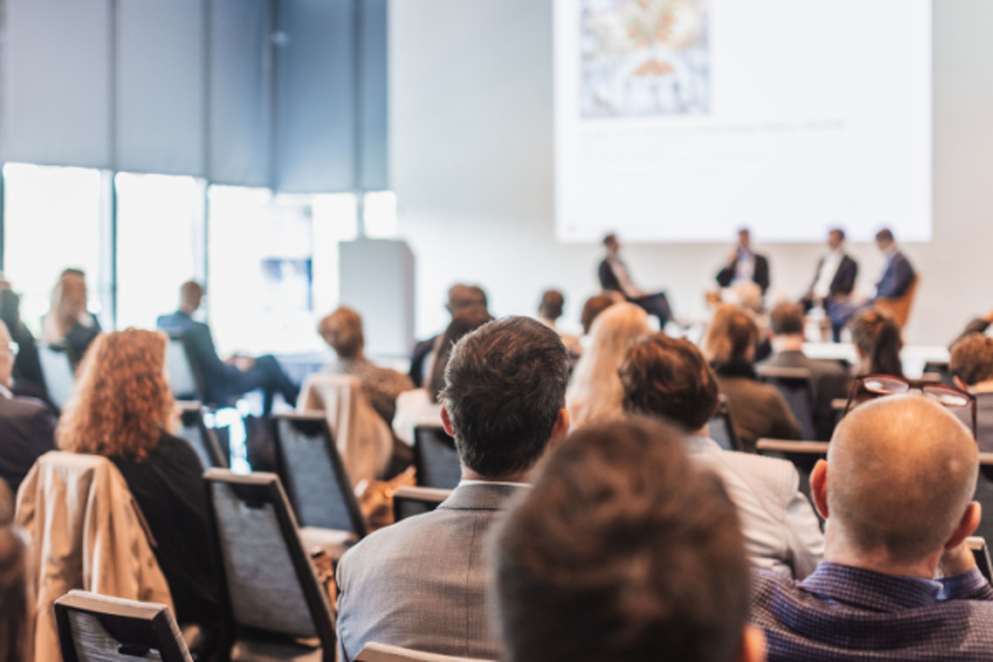corporate event attendees watch a presentation in a bright room
