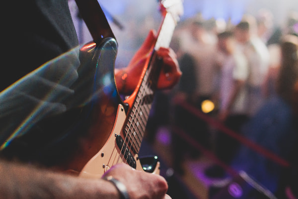 a guitarist on stage with a blurry crowd in the background