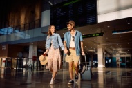 a young couple walks through the airport together holding hands